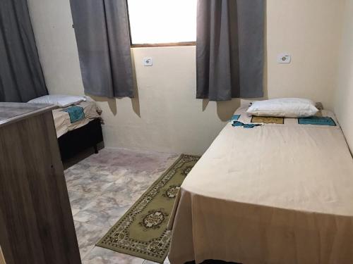 a small room with two beds and a window at Chalé Recanto Derrico in Santo Antônio do Pinhal