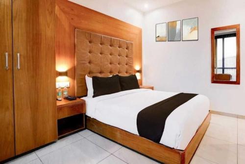 a bedroom with a large bed with a wooden headboard at Townhouse Oak Railway Junction Kota Formerly Hotel Crosslane in Nānta