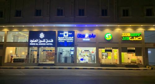 a store front at night with signs in the windows at فندق كنوز العنود مكة للغرف والأجنحة الفندقية - Knoz Al Anood Hotel Makkah For Hotel Rooms and Suites in Makkah