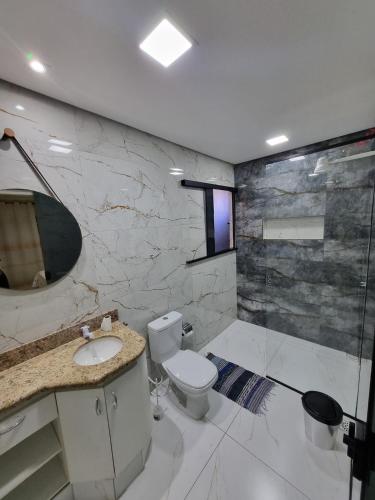 a bathroom with a toilet and a sink and a shower at Aconchego Paraíso 2 Shopping com Garagem e Suíte in São João del Rei