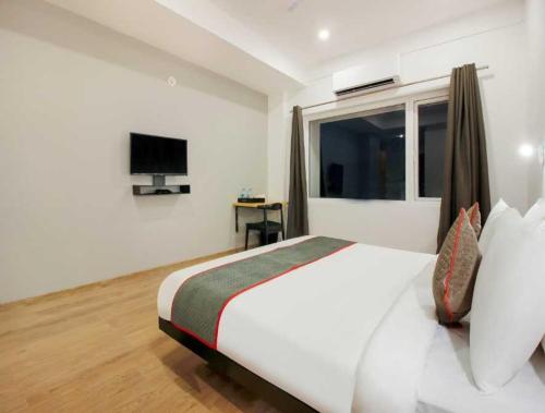 une chambre avec un grand lit blanc avec une fenêtre dans l'établissement Townhouse Rajahmundry City Centre Formerly Svas Inn, à Godāvari