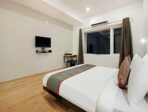 une chambre avec un grand lit blanc et une télévision dans l'établissement Townhouse Rajahmundry City Centre Formerly Svas Inn, à Godāvari