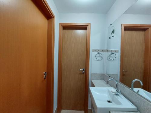 ein Badezimmer mit Waschbecken und Holztür in der Unterkunft Flat - Fiore Prime Flat Style - 5 pessoas - Apartamento - 5 andar in Caldas Novas