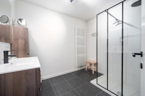 een badkamer met een wastafel en een glazen douche bij JoLi Beach Apartment in Middelkerke