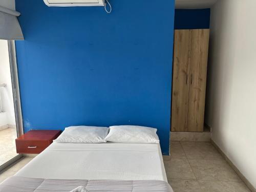 a bedroom with a blue wall and a bed at Hotel Maria del Mar planeta Rica in Planeta Rica
