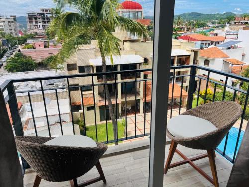 a balcony with two chairs and a view of a city at Life Bucerías, Modern Studio Near the Beach in Bucerías