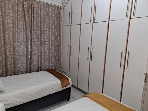 a bedroom with white cabinets and a bed at Overflowing Guest House in Durban