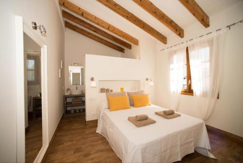 Un dormitorio con una cama blanca con almohadas naranjas. en Garbo by Vintage Travel, en Cala Morell