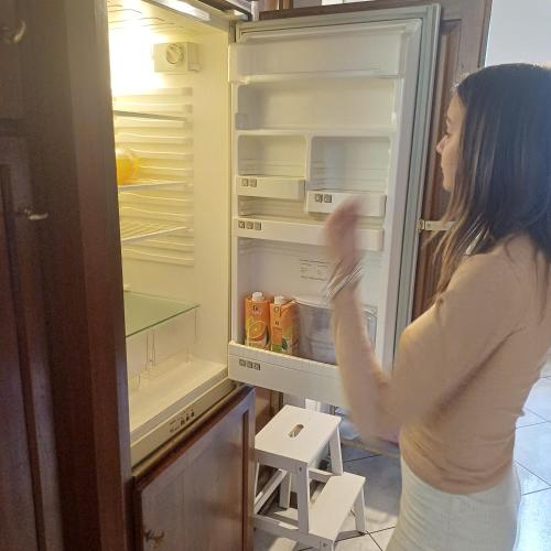 a woman is looking inside of an open refrigerator at Villa Azalea in San Fermo della Battaglia