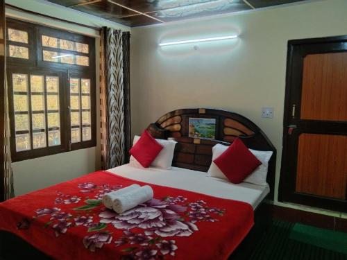 a bedroom with a bed with red sheets and flowers on it at Hotel classic kuppa sangla in Sāngla
