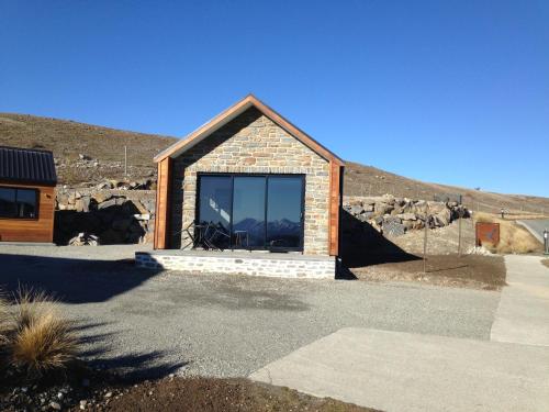 a small house with a large window on the side of it at Simply Stunning Studio 1 in Lake Tekapo
