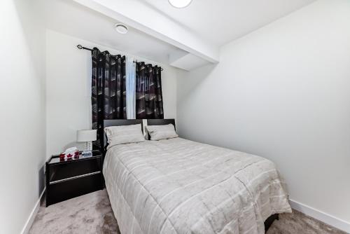 a white bedroom with a bed and a window at KimzNest in Edmonton
