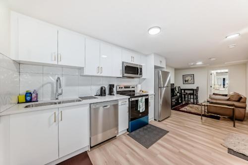 a kitchen with white cabinets and a living room at KimzNest in Edmonton