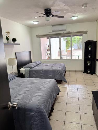 a bedroom with two beds and a ceiling fan at Casa Mel, Excelente ubicacion, seguridad in Cozumel