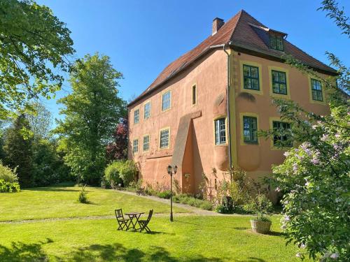 un grande edificio in mattoni con una panchina nell'erba di Wasserburg Turow a Glewitz