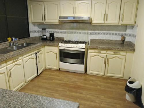 a kitchen with white cabinets and a stove and a sink at Hermoso departamento de 3 dormitorios para 10 personas en el centro histórico de Cuenca in Cuenca