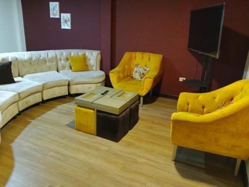 a living room with couches and chairs and a tv at Hermoso departamento de 3 dormitorios para 10 personas en el centro histórico de Cuenca in Cuenca