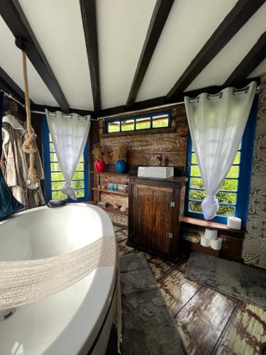 a bathroom with a tub and a sink and windows at OctoCabana com banheira e mirante privativo in Urubici