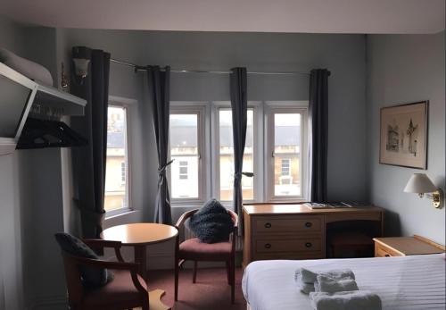 a bedroom with a bed and a desk and windows at En-suite Double Room in Bath