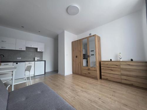 a living room with a kitchen and a wooden cabinet at Niepodległości Park View Studio by BookingHost in Kraśnik