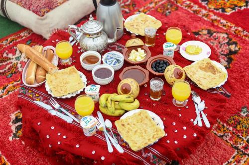 uma mesa com alimentos e bebidas para o café da manhã sobre um cobertor vermelho em Blue Rina Hostel em Agadir