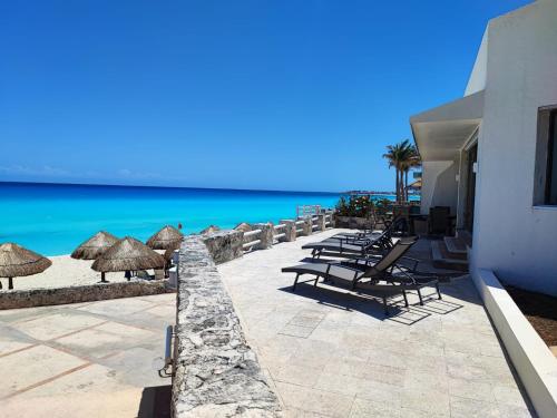 a patio with chairs and umbrellas on the beach at Beach Front Flat!!! in Cancún