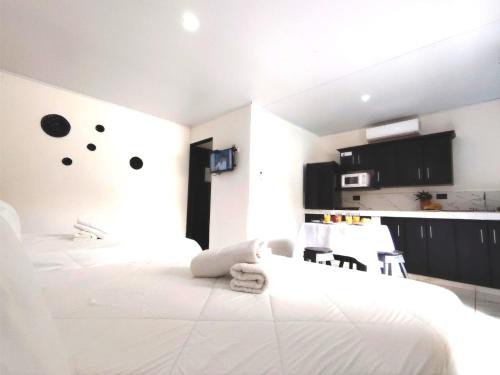 a white bedroom with a white bed and a kitchen at Casa Chika Playa Grande Guanacaste 3 in Cuajiniquil