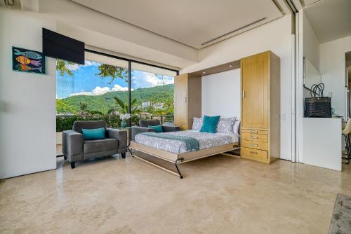 Un dormitorio con una cama y una silla y una ventana. en Maxwell Collection Romantic Zone, en Puerto Vallarta