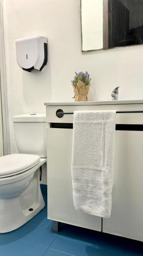 a white bathroom with a toilet and a towel at Oi Braga in Braga