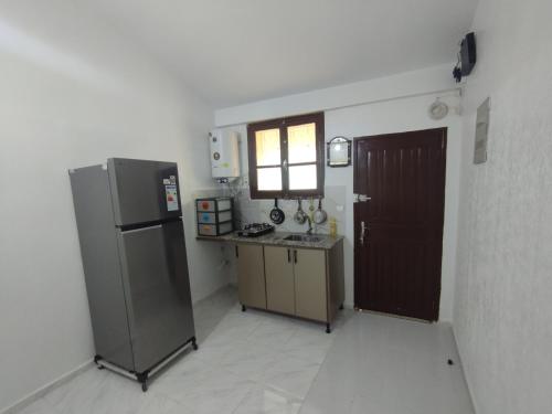 a kitchen with a refrigerator and a table and a window at Cristal hospitality in Imouzzer Kandar