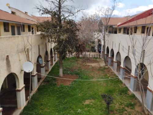 a courtyard of a school with arches and a fence at Cristal hospitality in Imouzzer Kandar