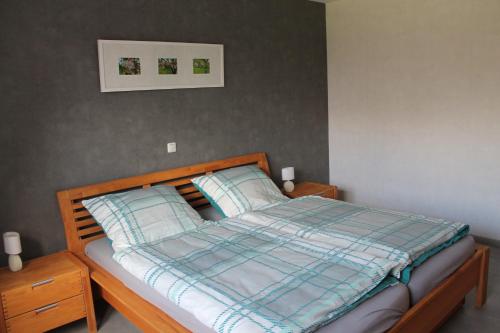 ein Bett mit einer blauen karierten Decke und 2 Kissen in der Unterkunft Hardthof - Hürtgenwald in Hürtgenwald
