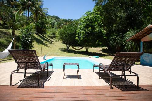 zwei Stühle und ein Tisch neben einem Schwimmbecken in der Unterkunft Sitio Novo Dia in Saquarema