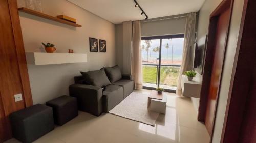 ein Wohnzimmer mit einer Couch und einem Fenster in der Unterkunft Apto Vista Mar Área Gourmet Piscina 2 Suítes in São Bento