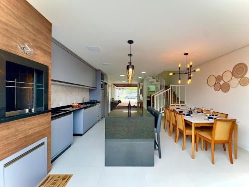 Una cocina y un comedor con mesa y sillas. en Casa Completa com Churrasqueira Wi-Fi e Garagem para 2 Carros a 400m da PRAIA Acomoda 8 Pessoas, 3 suites com Ar-Condicionado, en Piçarras