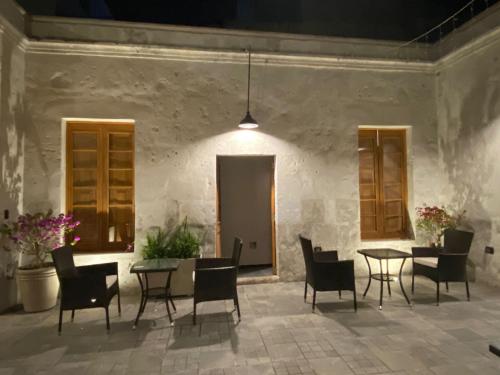 a patio with chairs and tables and a wall at Inti Paqari in Arequipa
