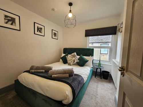 Schlafzimmer mit einem Bett mit einem grünen Kopfteil und einem Fenster in der Unterkunft CityPad Cardiff in Cardiff