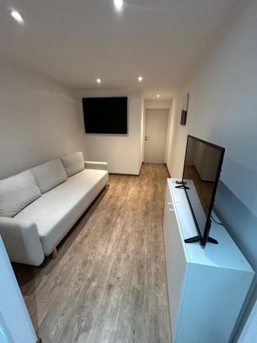 a living room with a white couch and a flat screen tv at Le Loft Minimal in Huy