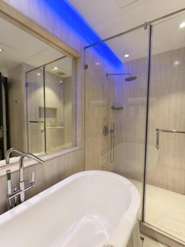 a bathroom with a tub and a glass shower at Savoy Grande Hotel in Seef