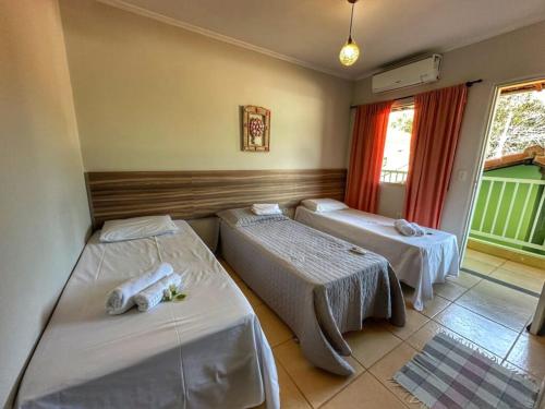 une chambre avec deux lits et une fenêtre dans l'établissement Pousada Gaia Canastra, à São João Batista do Glória