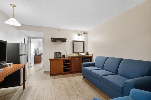a living room with a blue couch and a tv at Country Inn & Suites by Radisson, Saskatoon, SK in Saskatoon