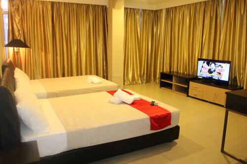 a hotel room with two beds and a flat screen tv at T Hotel Jalan Tar in Kuala Lumpur