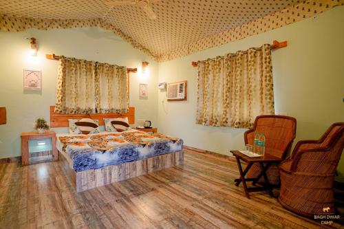 Un dormitorio con una cama y dos sillas. en Baagh Dwar Camp & Resort, en Khilchīpur