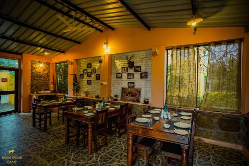 a dining room with tables and chairs and a fireplace at Ranthambhore Bagh Dwar Camp in Khilchipur