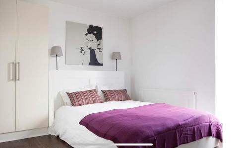 a white bedroom with a bed with a purple blanket at Lovely Duplex close to city and Guinness Factory in Dublin