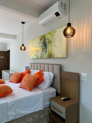a bedroom with a bed with orange pillows and a painting at Sítio Esperança e Fé in Ribeirão das Neves