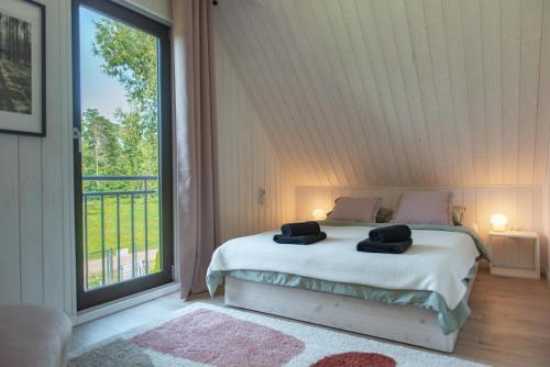 a bedroom with a bed and a large window at Uroczysko nad Pilicą Sauna & Balia in Pilica