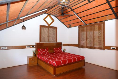 a bedroom with a bed with a red comforter at Chettinad Courtyard By Shivalaya Coimbatore in Alāndurai