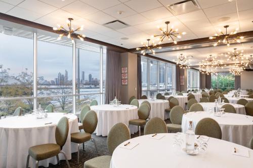 a dining room with white tables and chairs and large windows at Sable At Navy Pier Chicago, Curio Collection By Hilton in Chicago