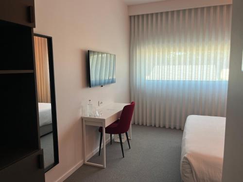 a hotel room with a desk and a bed at REDNYX Hotel in Cortegaça